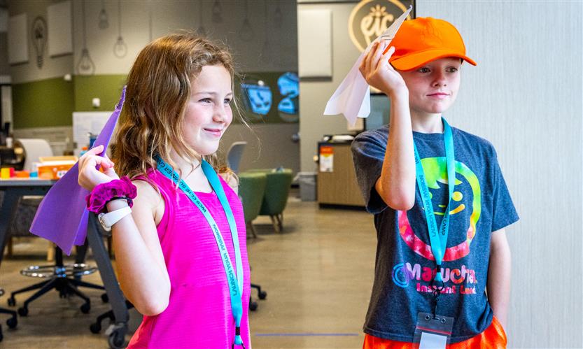 Two girls prepare to throw paper airplanes